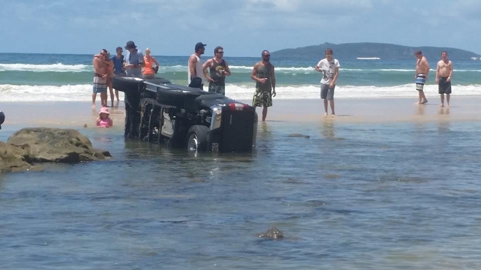 An upturned vehicle on the beach makes for considerable deliberation.